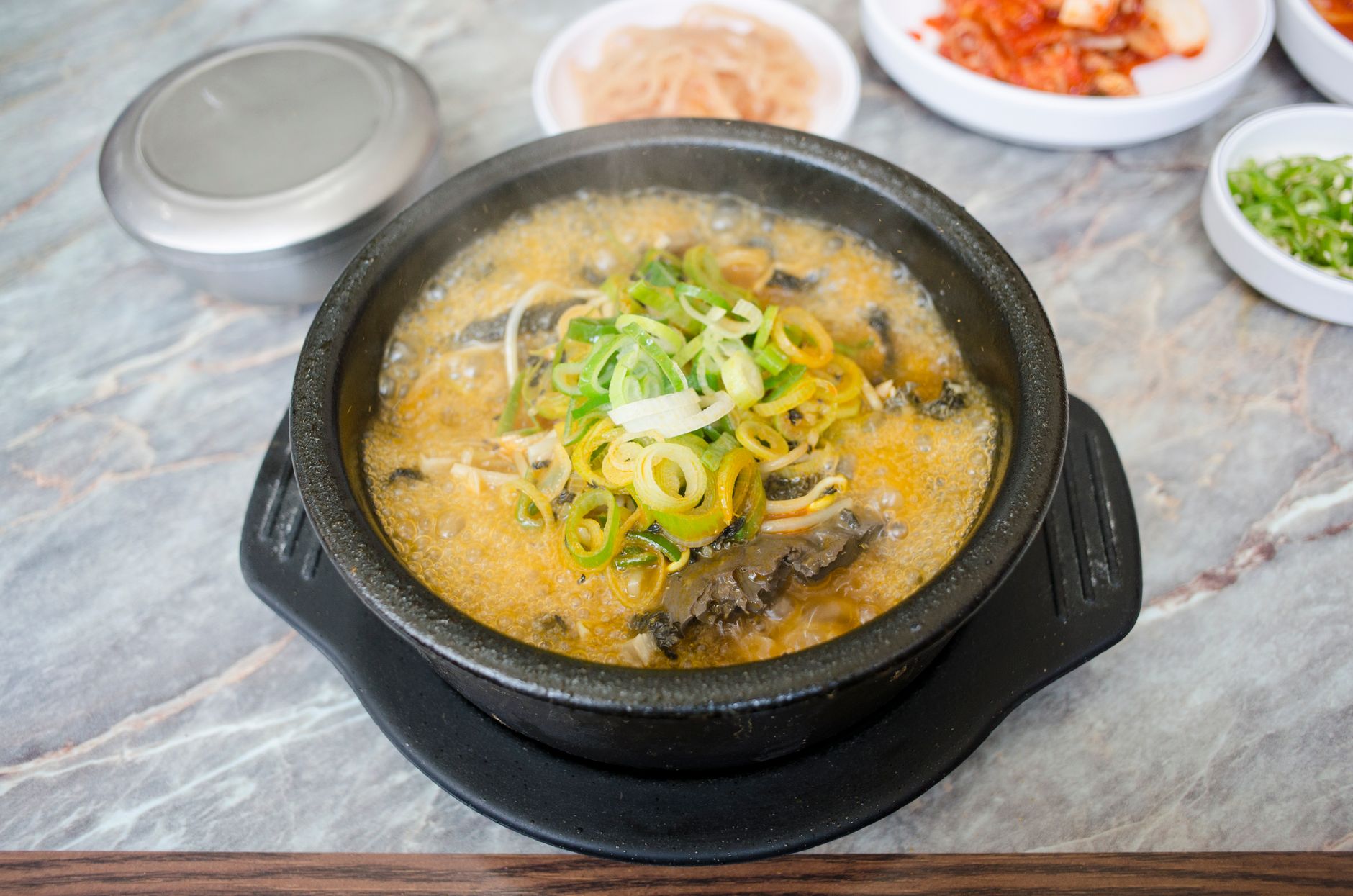 채소와 고명이 올라간 뜨거운 뚝배기 국물 요리